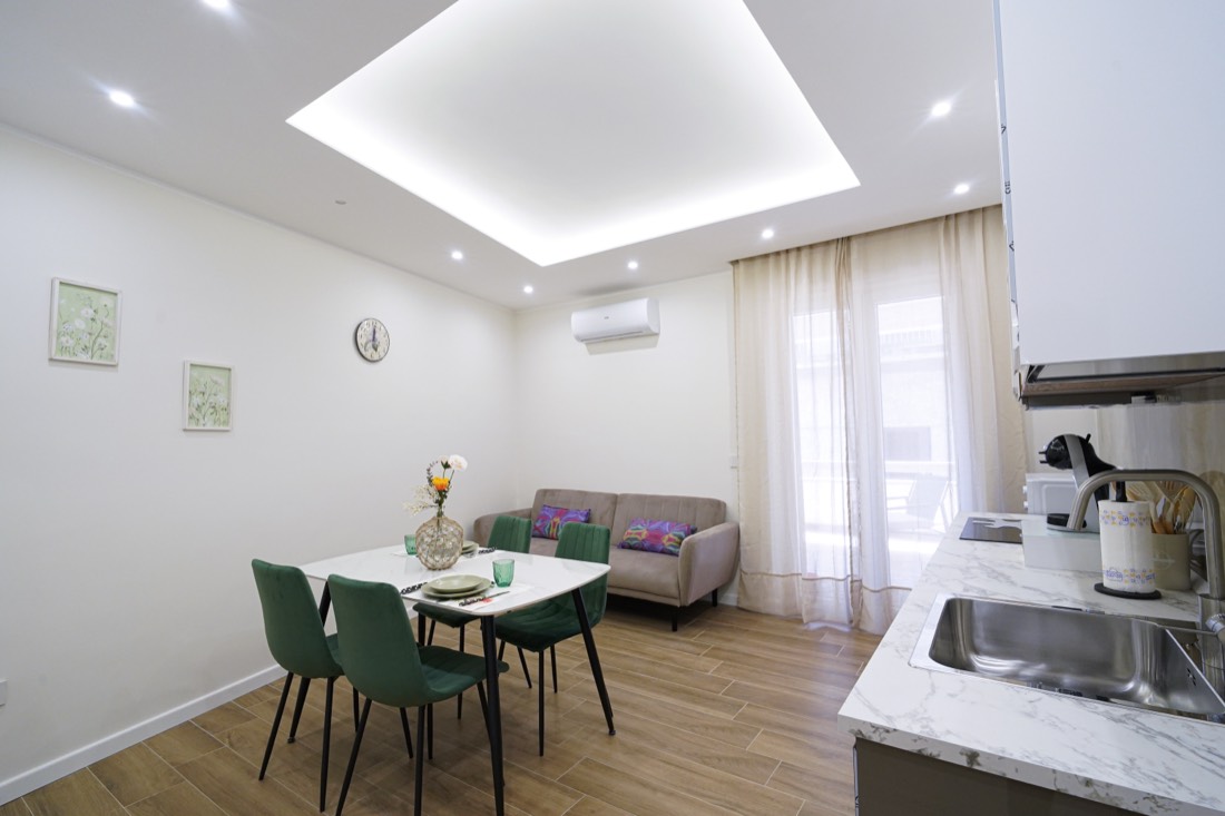 Zona living con divano, tavolo da pranzo e sedie in velluto verde